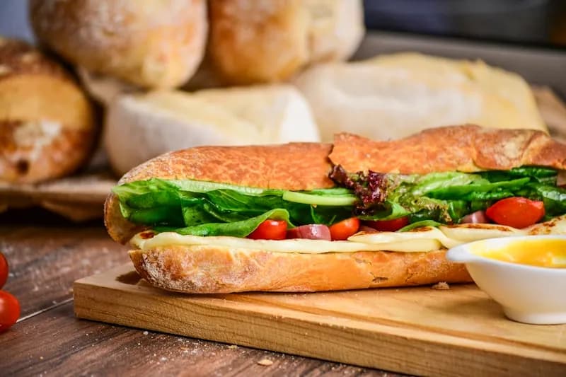 Stacked deli sandwich with fresh ingredients on rustic counter