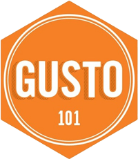 The industrial-style interior of Gusto 101 featuring exposed brick, wooden beams, and warm lighting.