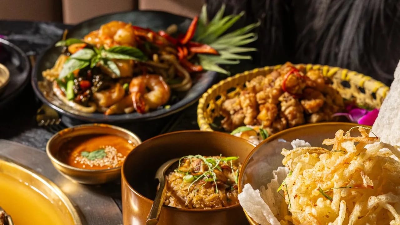 A tabletop mookata grill with meats searing on the dome and vegetables simmering in the broth moat.