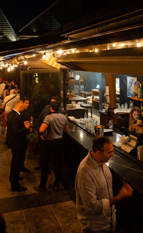 Guests at The Broadview Hotel Rooftop bar at night