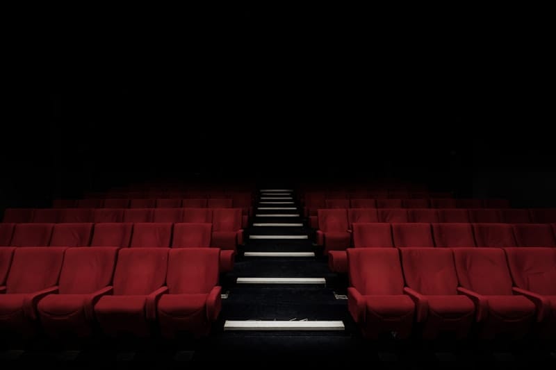 Rows of empty red cinema seats in a darkened theatre